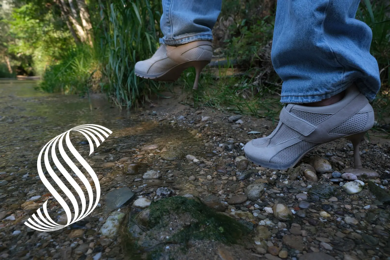 Two pairs of feet in heel-soled mesh sneakers stepping off a grassy creek bank onto wet gravel, with the Sneex spiral mark at lower left.